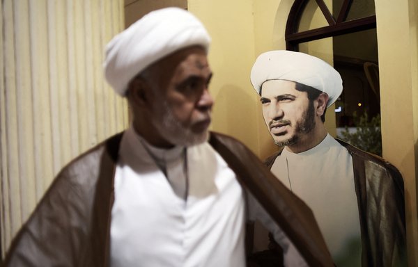 A Bahraini cleric walks past a cardboard cutout bearing the portrait of Sheikh Ali Salman, leader of the banned Shia opposition movement Al-Wefaq, on May 29, 2016. [Mohammed al-Sheikh/AFP]