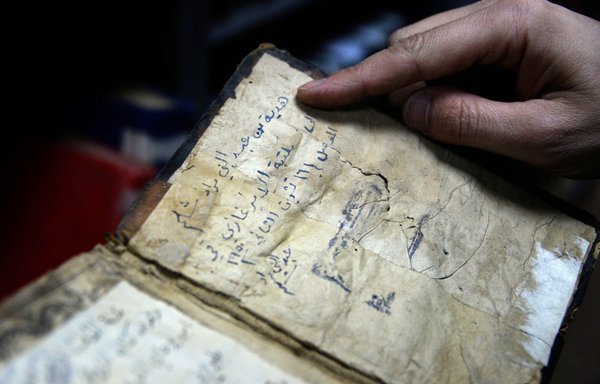 A librarian shows a book from the collection of Mosul central library on January 31. [Zaid al-Obeidi/AFP]