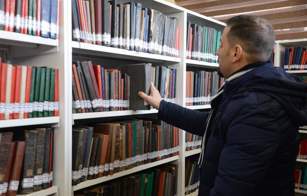 A man on January 31 picks a book from the collection of Mosul central library, founded in 1921. [Zaid al-Obeidi/AFP]
