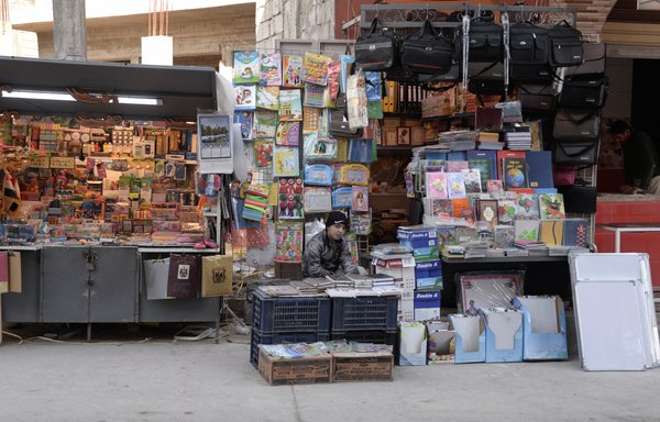 An Iraqi youth sits at a stall for books and school supplies in Iraq's northern city of Mosul on January 31. [Zaid al-Obeidi/AFP]