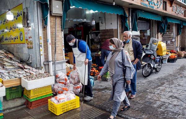 A woman walks past a fishmonger's shop in the south of Tehran on February 20. As Iran sinks deeper into economic crisis, many struggle to afford food staples. [AFP]