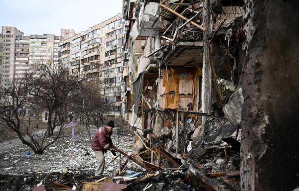 رجل يرفع الحطام في مبنى سكني مدمر في العاصمة الأوكرانية كييف، بعد تعرضه للقصف بقنبلة روسية يوم 25 شباط/فبراير. باتت القوات الروسية إعلى قاب قوسين من المدينة. [دانيال ليل/وكالة الصحافة الفرنسية]