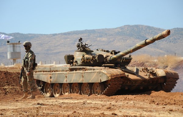 A Russian officer stands next to a Syrian army tank during an instruction session with Russian military trainers on September 24, 2019, at an army base in Yafour. [Maxime Popov/AFP]