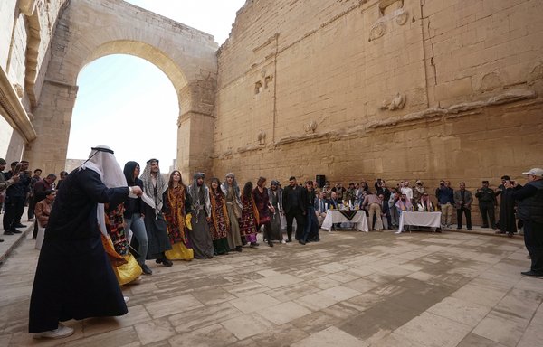 Iraqis perform a traditional dance during a February 24 ceremony to unveil restored sculptures that were vandalised by ISIS in the ancient city of Hatra south of Mosul. [Zaid al-Obeidi/AFP]