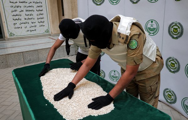 Officers of the Directorate of Narcotics Control of Saudi Arabia's Interior Ministry sort through Captagon tablets seized during a special operation in Jeddah on March 1. [Fayez Nureldine/AFP]