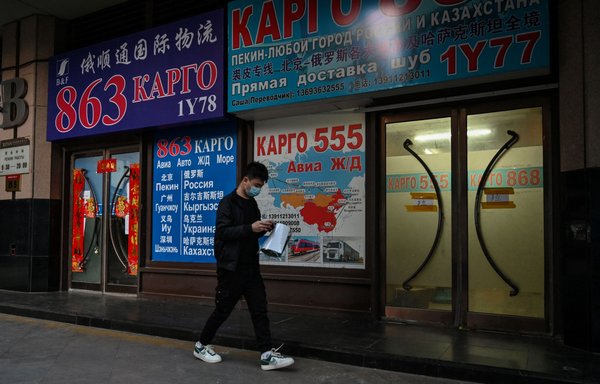 A man walks past a store advertising cargo shipping to Russia and other countries, along a street in Beijing on March 4. [Hector Retamal/AFP]