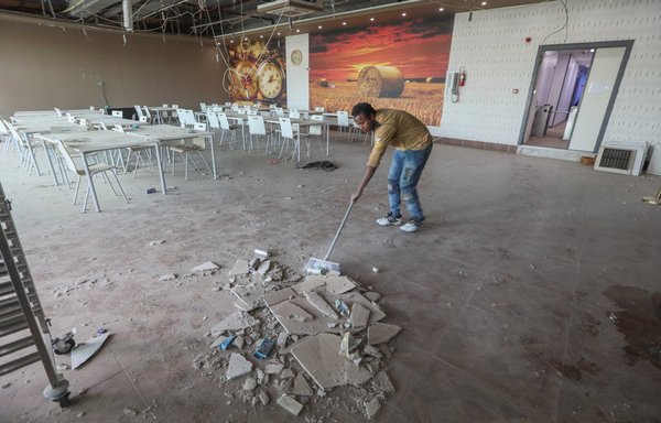 A man cleans up debris in the damaged studios of the Kurdistan24 TV building, after an overnight attack in Erbil on March 13 that was claimed by the IRGC. [Safin Hamed/AFP]