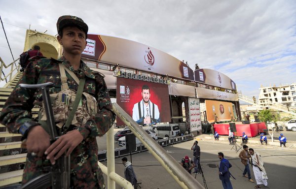 Fighters loyal to the Houthis stand guard while supporters of the Iran-backed group attend a speech given on a screen by the group's leader Abdulmalik al-Houthi during a rally in Sanaa, on September 2. [Mohammed Huwais/AFP]