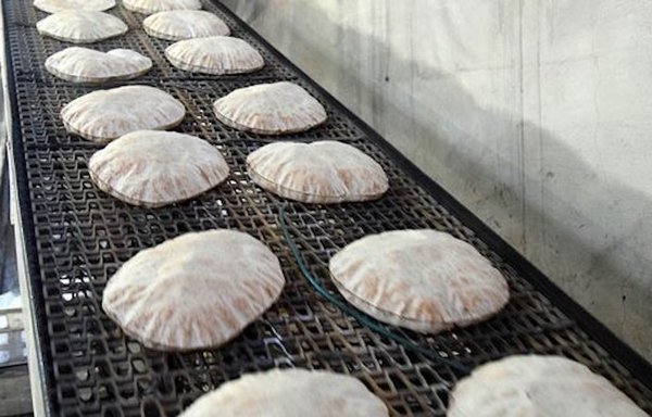 أرغفة الخبز الطازج تبرّد في مخبز في سوريا، حيث قال مراقبون إن النظام يحاول التخفيف من وطأة أزمة القمح المنتظرة بسبب اعتماده على روسيا. [سانا]