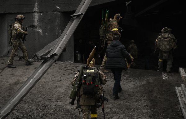 Ukrainian servicemen walk across a destroyed bridge towards the city of Irpin, northwest of Kyiv, during heavy shelling and bombing on March 5. [Aris Messinis/AFP]