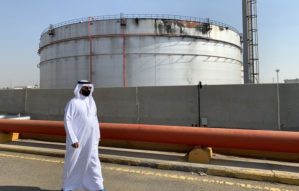 A man walks past a damaged silo at the Saudi Aramco oil facility in Saudi Arabia's Red Sea city of Jeddah on November 24, 2020. Yemen's Houthis launched drone and missile attacks on Saudi facilities on March 19, including on an Aramco site. [Fayez Nureldine/AFP]