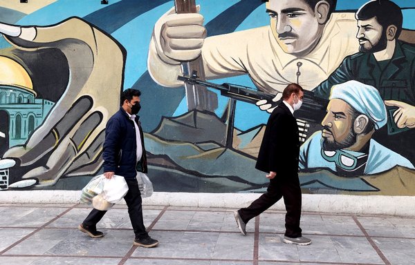 رجال إيرانيون يمرون أمام لوحة جدارية في العاصمة طهران يوم 9 آذار/مارس. ويطالب الإيرانيون الجمهورية الإسلامية بإعادة النظر في خطط اعتمادها على التجارة مع الشرق كحل لمشاكل بلادهم الاقتصادية الراهنة. [عطا كيناري/وكالة الصحافة الفرنسية]