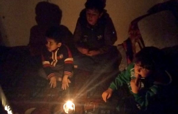 أطفال يتجمعون حول شمعة أثناء انقطاع التيار في سهل البقاع اللبناني. [صوت اللاجئ السوري في لبنان]