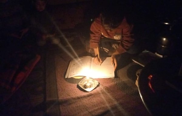 طفل لاجئ يؤدي فروضه المدرسية على ضوء شمعة في مخيم بسهل البقاع اللبناني. [صوت اللاجئ السوري في لبنان]