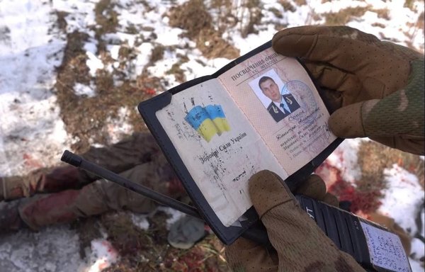 أحد عناصر المرتزقة الروس يحمل بطاقة عسكرية لضابط أوكراني تم اعدامه علنا. [ريفرس سايد أوف ذي ميدال/تيلغرام]