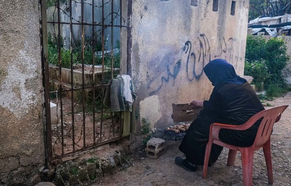زنی در روز ۲۷ فروردین ۱۴۰۰ در قبرستان غرابه شهر بندری طرابلس در شمال لبنان برای آماده کردن غذای افطار در حال کباب کردن یک مرغ است. در این منطقه خانواده‌های به حاشیه رانده شده زندگی می کنند. [ابراهیم شلهوب/ خبرگزاری فرانسه]