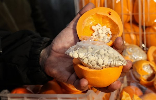 In this file photo taken December 29, a man shows fake oranges filled with Captagon pills hidden in boxes containing real fruit, after the shipment was intercepted by the customs and anti-drug brigade at the Beirut port. [Anwar Amro/AFP]