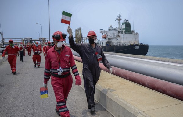 یک کارگر شرکت نفت دولتی ونزوئلا روز ۴ خرداد ۱۳۹۹ در حالی که نفتکش فورچون با پرچم ایران در پالایشگاه ال پالیتو در پورتو کابلو ونزوئلا پهلو می گیرد، پرچم ایران را تکان می‌دهد. [خبرگزاری فرانسه]