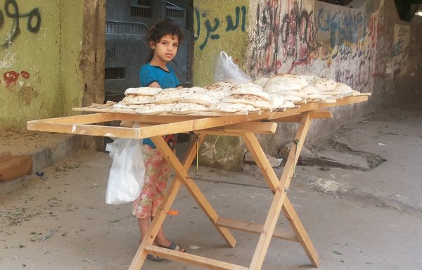 طفلة تبيع خبزا لا تدعمه الحكومة في أحد شوارع القاهرة. [وليد أبو الخير/فريق عمل المشارق]