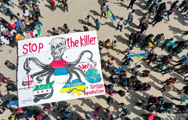 This picture taken April 1 shows a giant sign depicting Russia's President Vladimir Putin as an octopus with its arms wrapping around Georgia, Syria, Ukraine and the world during a demonstration in Binnish in Syria's Idlib province against Russia's invasion of Ukraine. [Omar Haj Kadour/AFP]