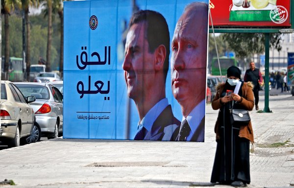A banner depicting Syrian President Bashar al-Assad and Russian President Vladimir Putin and reading 'Justice Prevails' is displayed along a highway in the Syrian capital Damascus on March 8. [Louai Beshara/AFP]