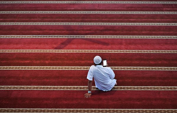 A man reads a digital copy of the Koran on his phone at a mosque in Indonesia on April 6. [Chaideer Mahyuddin/AFP]
