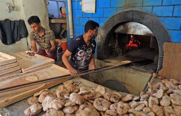 عمال يجهزون الخبر في مخبر في صنعاء يوم 28 شباط/فبراير. إن غزو روسيا لأوكرانيا يمكن أن يعني انخفاضا في الخبز في اليمن. [محمد حويس/وكالة الصحافة الفرنسية]