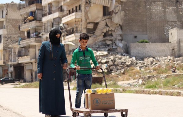 A mother and son take home food aid they have received from the World Food Programme office in the Syrian city of Aleppo in 2020. [WFP]