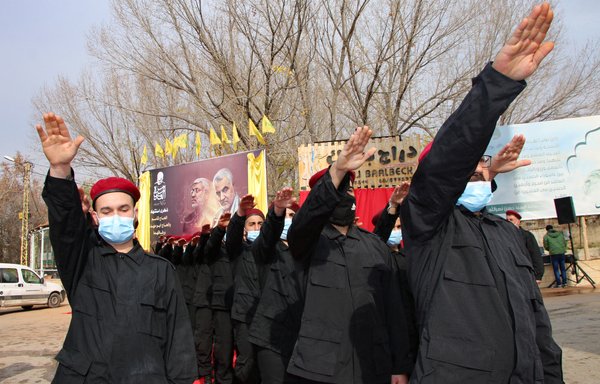 Hizbullah elements take part in a parade under a large poster of slain Iraqi commander Abu Mahdi al-Muhandis and IRGC commander Qassem Soleimani on January 2, 2021, in the Lebanese city of Baalbek in the eastern Bekaa Valley. [AFP]