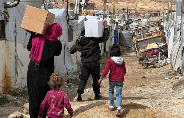 A family carries boxes of food aid from international aid organisations in Lebanon on April 9. [Twitter]