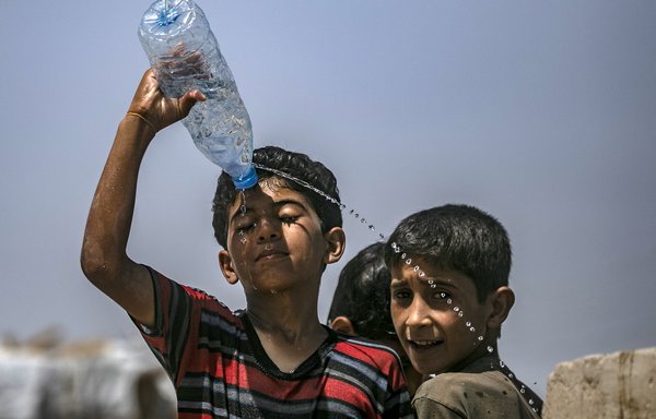 Boys cool themselves off inside al-Hol camp in al-Hasakeh province, northeastern Syria on June 2, 2019. Teenage boys at the camp have been a target for ISIS recruiters. [Delil Souleiman/AFP]