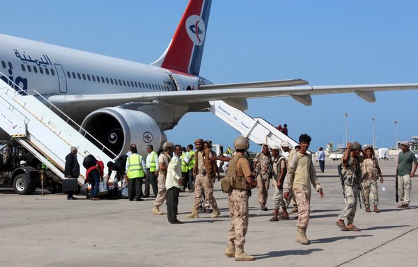 Pro-government Yemeni forces stand guard as passengers disembark from a Yemenia aircraft coming from Jordan on May 5, 2016, at Aden International Airport. [Saleh al-Obeidi/AFP]