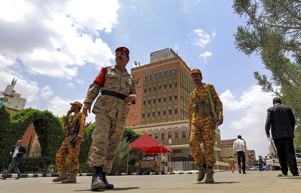 Security personnel loyal to the Iran-backed Houthis walk about outside the Central Bank headquarters in Houthi-held Sanaa on June 23. [Mohammed Huwais/AFP]