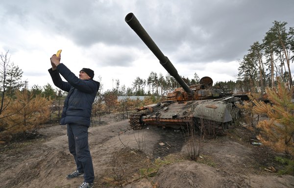 A man takes a selfie in front of a destroyed Russian tank in Andriivka village, Kyiv province, Ukraine, April 17. [Sergei Supinsky/AFP]