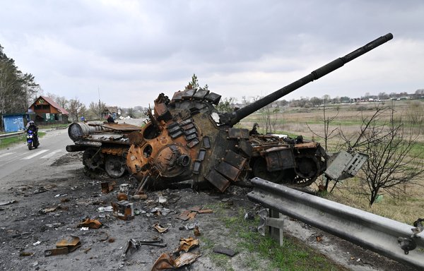 A man rides a motorbike past a destroyed Russian tank in Rusaniv village, Kyiv province, Ukraine, April 16. [Genya Savilov/AFP]