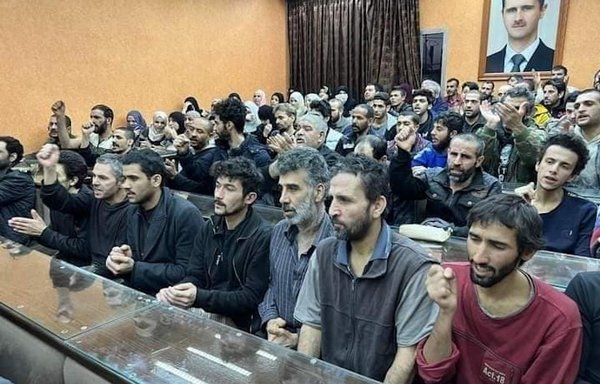 زندانیانی که با عفو ریاست‌جمهوری آزاد شده‌اند، در یک ساختمان دولتی در استان دمشق زیر عکس بشار اسد دیده می‌شوند. بسیاری از مردم سوریه رژیم آن کشور را به استفاده از فرمان عفو عمومی به‌عنوان یک ترفند تبلیغاتی متهم می‌کنند. [فیسبوک]