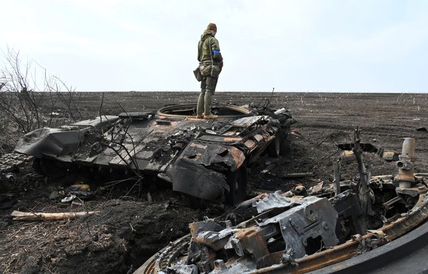 A Ukrainian soldier stands on the wreckage of a burnt Russian tank outside of the village of Mala Rogan, east of Kharkiv, on April 1, amid Russian invasion of Ukraine. [Sergey Bobok/AFP]