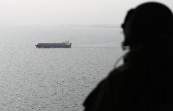 A picture taken August 10, 2018, shows an Emirati soldier watching from a military plane a ship crossing through Bab al-Mandeb strait, which separates the Arabian Peninsula from East Africa. The UAE is a member of a multinational maritime coalition that patrols the Red Sea. [Karim Sahib/AFP]