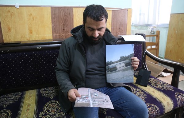 Syrian activist Omar al-Alewi holds a photo and a map of his property, from which he was displaced in October 2015. [Ali Hajj Suleiman]