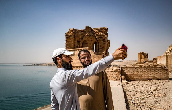 رجال يقفون لالتقاط صورة سلفي عند أطلال قلعة جعبر في خزان بحيرة الأسد في محافظة الرقة يوم 3 حزيران/يونيو. [دليل سليمان/وكالة الصحافة الفرنسية]