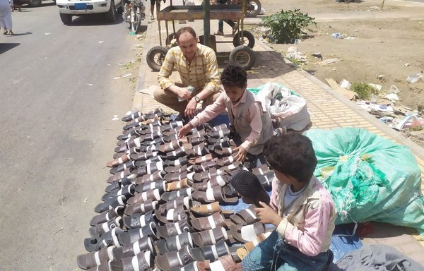 لؤي البالغ من العمر وشقيقه راكان تركا المدرسة ويبيعان الأحذية على رصيف في صنعاء الخاضعة للحوثيين للمساعدة في تأمين لقمة العيش لعائلتهما. [هيثم محمد/المشارق]