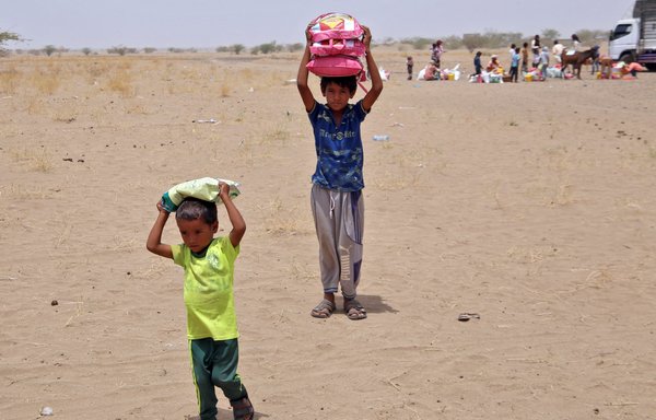 يمنيون نزحوا جراء الحرب يتلقون المساعدات الغذائية والمستلزمات لتلبية متطلباتهم الأساسية في مخيم في ناحية حيس بالحديدة بتاريخ 29 آذار/مارس. وتضاعفت أسعار المواد الغذائية منذ العام الماضي، ومع تأمين أوكرانيا نحو ثلث واردات القمح اليمنية، هناك مخاوف من تفاقم حالة المجاعة. [خالد زياد/وكالة الصحافة الفرنسية]