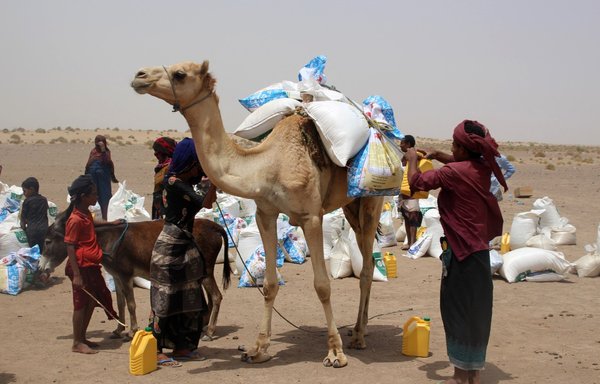 عائلات يمنية فقيرة تتلقى حصص الطحين ومواد غذائية أخرى من الجمعيات الخيرية في محافظة لحج الجنوبية في 29 آذار/مارس. [صالح العبيدي/وكالة الصحافة الفرنسية]