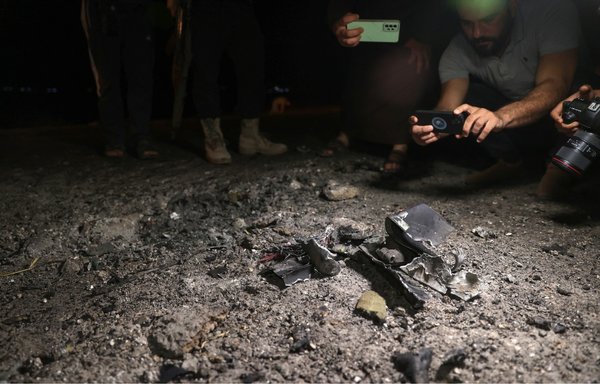 Fighters affiliated with Tahrir al-Sham and local journalists take pictures in the early morning hours of June 28 of the site of a drone attack that killed Hurras al-Deen leader Abu Hamzah al-Yemeni on the eastern edge of Syria's Idlib province. [Omar Haj Kadour/AFP]