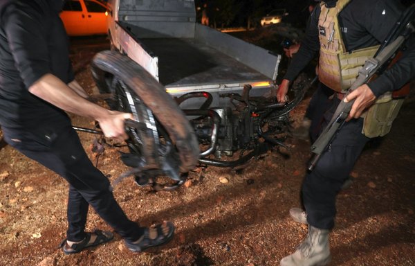 Fighters affiliated with Tahrir al-Sham transport the remains of a motorcycle ridden by Hurras al-Deen chief Abu Hamzah al-Yemeni, who was targeted in a drone attack on the eastern edge of Idlib province, early on June 28. [Omar Haj Kadour/AFP]