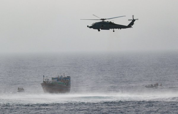 An MH-60R Seahawk provides aerial support to an interdiction team from guided-missile destroyer USS Momsen approaching a fishing vessel on May 16. The vessel was seized while transiting international waters in the Gulf of Oman. [US Navy]