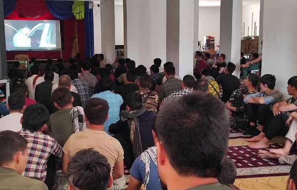 Fatemiyoun Division militiamen in Syria watch a documentary about the battle of Palmyra at the headquarters of the Martyr Sayed al-Hakim on June 6. [Fatemiyoun account, Telegram]