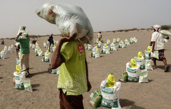 Displaced Yemenis receive food and supplies at a camp in Hays district of al-Hodeidah on July 6. [Khaled Ziad/AFP]