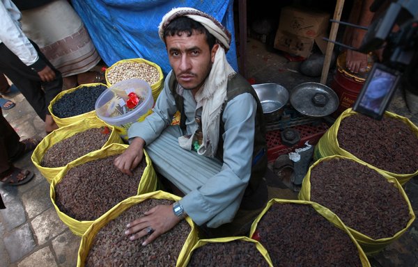 روز ٢١ تیرماه ١٣٩٤، یک فروشندۀ یمنی در بازاری در صنعا، آجیل و کشمش می‌فروشد. [محمد حویص/خبرگزاری فرانسه]
