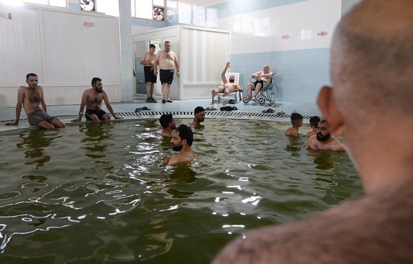 Men gather at Hamam al-Alil baths, south of the northern Iraqi city of Mosul, on June 30. The spa and surrounding village are known for massacres committed by ISIS during its occupation of the area. [Zaid al-Obeidi/AFP]